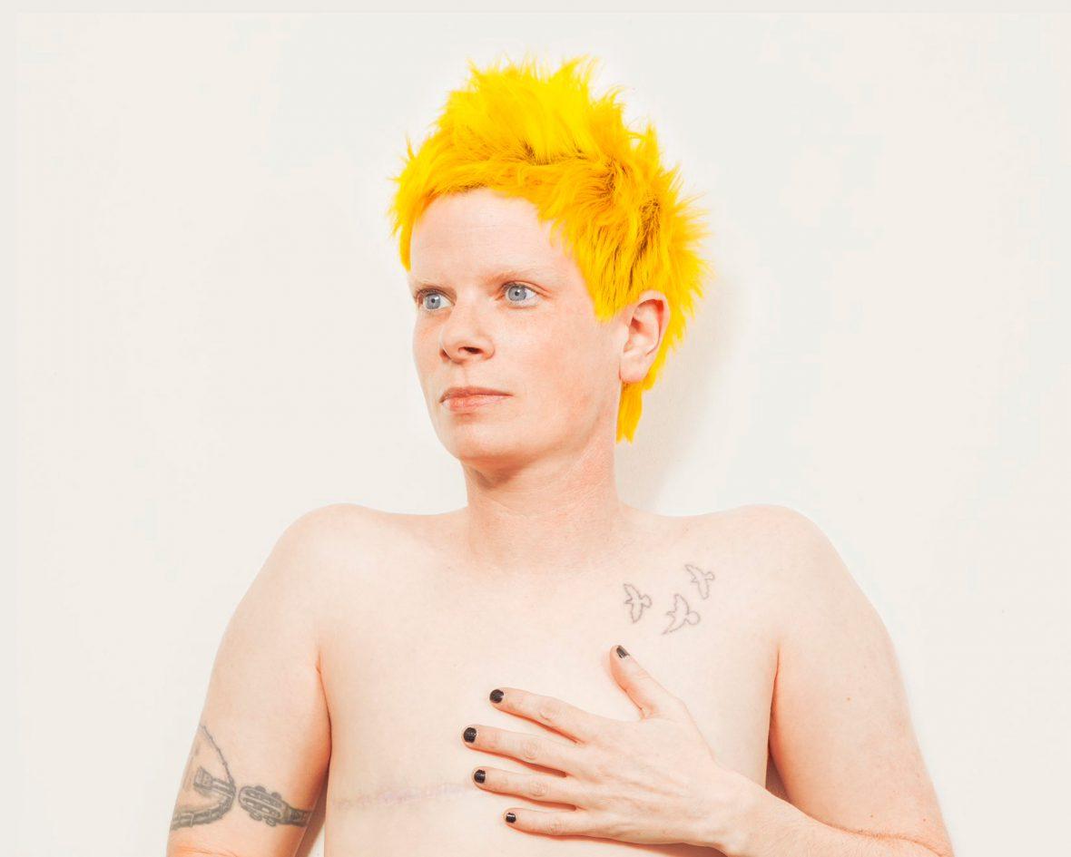 Portrait of Rae against a white backdrop with bright yellow short hair.